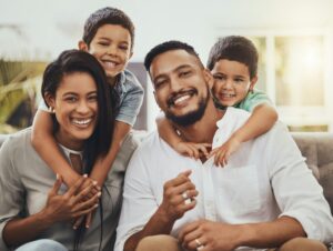 Mother, father and children hug for family portrait with smile relaxing together for holiday or wee